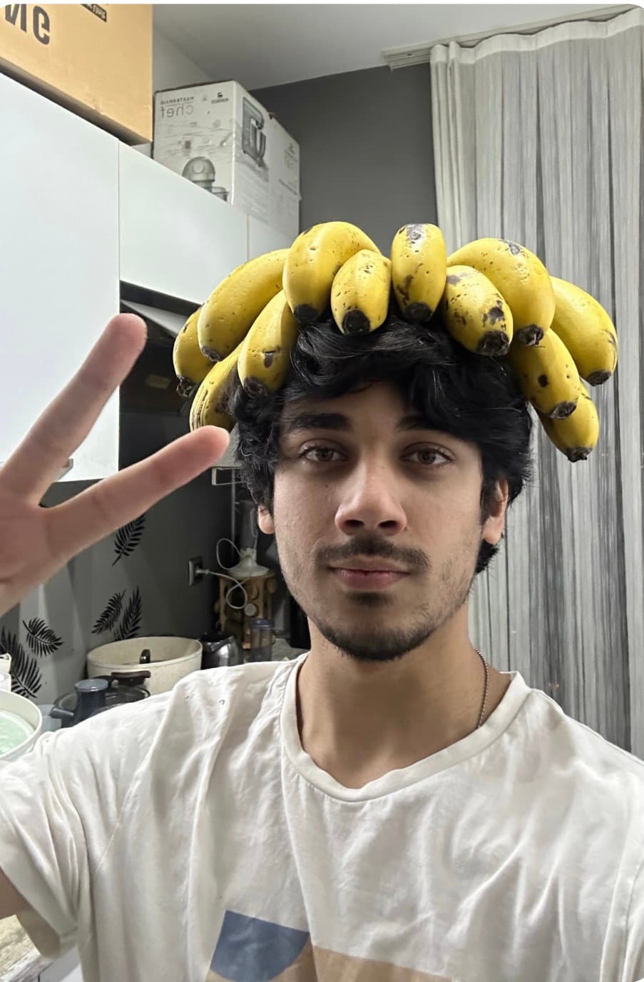 ryan balancing a bunch of bananas on his head while throwing a peace sign